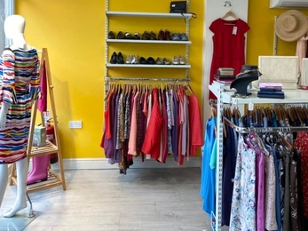View through a shop with rails of clothes and bright yellow walls