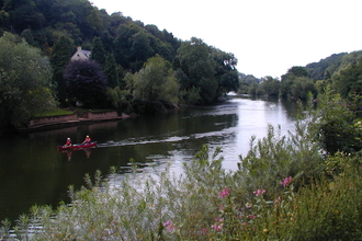 River bordered with vegetation with canoe in centre