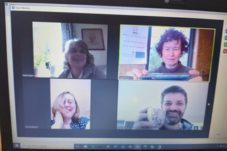 Photo of screen with four people on a video call.
