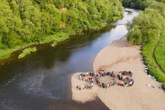 Letters SOS spelt out by people stood on riverside beach