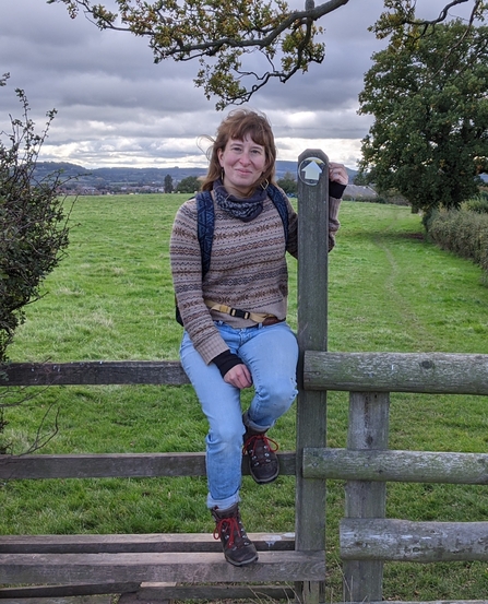 Woman sat on stile with fields behind