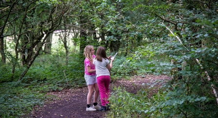 Two girls stood together in a woodland