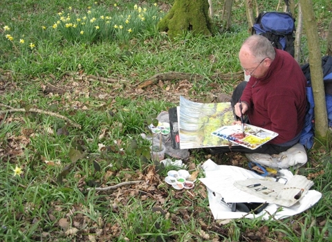 Artist sat in a woodland painting