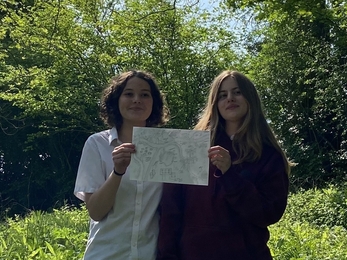 Two girls holding up a piece of paper 