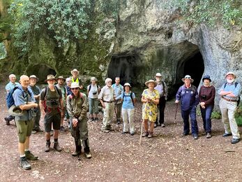 Group of around 20 people stood outside caves in sunshine