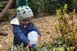 Young girl watering plants with upcycled milk carton