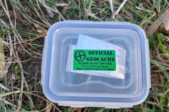 Plastic box with green sticker on lid on the grass