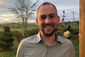 Man in grey shirt smiling at camera