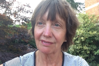 Portrait photo of woman's head and shoulders with short brown hair wearing a blue and white striped T-shirt