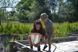 Woman kneeling looking into a net with young boy beside her