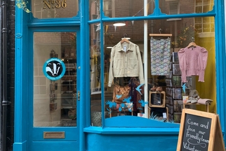 Shop window with blue paintwork and clothes hanging in the window