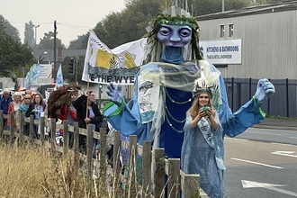 Huge puppet woman leading procession down street