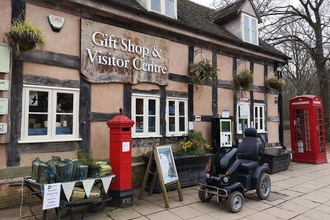A shiny black tramper mobility vehicle parked outside the visitor centre a Queenswood Country Park