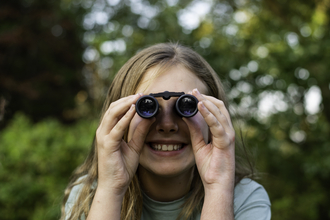 Girl using binoculars looking straight at camera