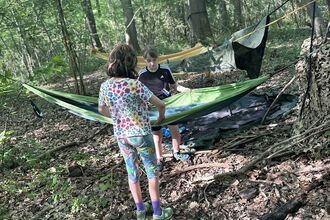 Two children with hammocks in a woodland
