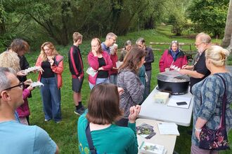 Group of people stood around two tables outside, one with a circular box on