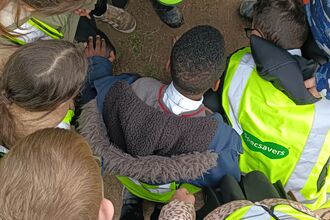 School children bent down looking at an earthworm