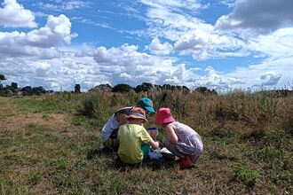 Four small children sat together in a field in summer
