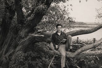 A young man sitting on a tree on the banks of the Canny Brook
