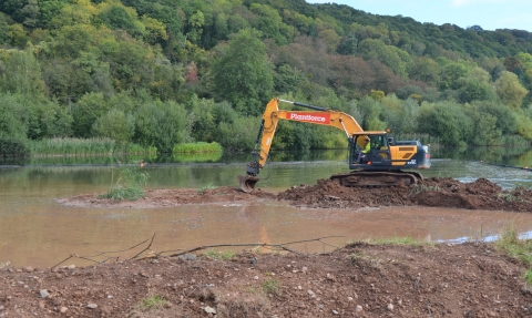 Digger moving earth at lake edge