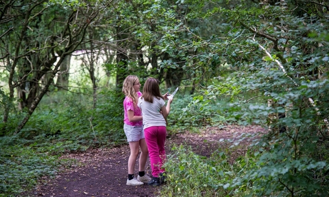 Two girls stood together in a woodland