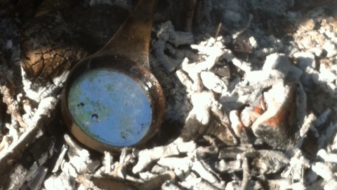 Molten pewter in a ladle over hot ashes