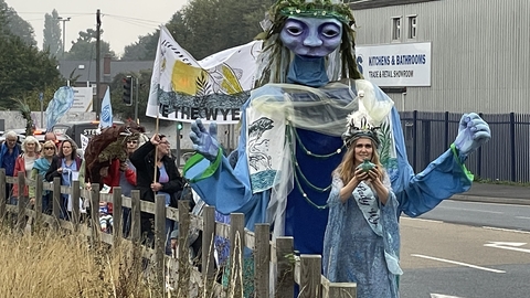 Huge puppet woman leading procession down street