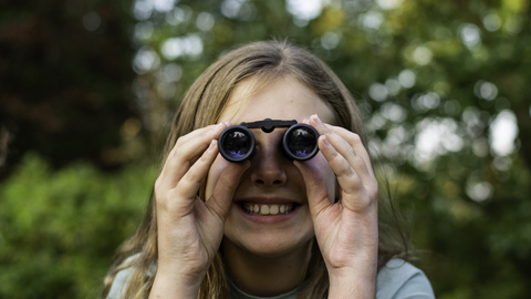 Girl using binoculars looking straight at camera