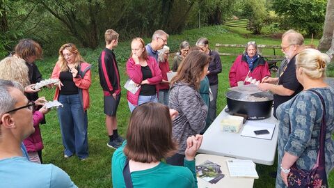 Group of people stood around two tables outside, one with a circular box on
