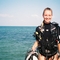 Woman in black top and diving gear stood beside sea