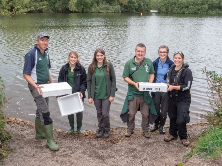 Group portrait staff and volunteers with boxes of elvers in front of the lake