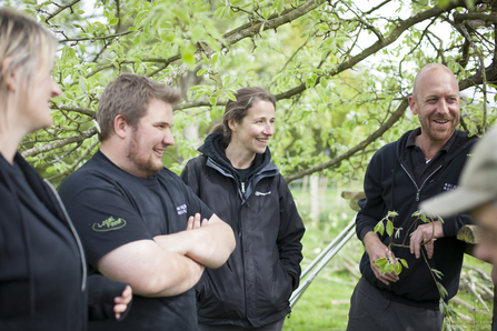Group of people chatting together in an orchard setting