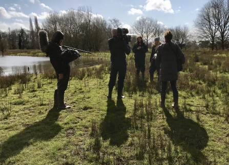 Camera crew filming two people in open countryside