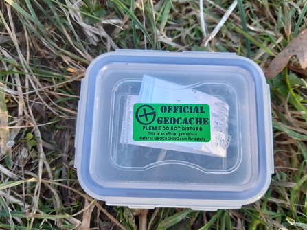 Plastic box with green sticker on lid on the grass