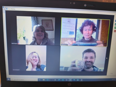 Photo of screen with four people on a video call.