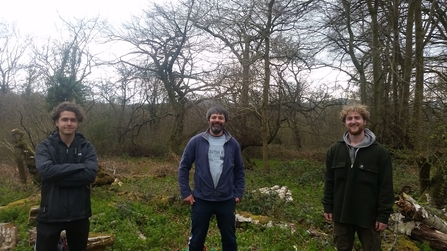 3 men socially distanced standing smiling in a woodland