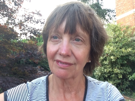 Portrait photo of woman's head and shoulders with short brown hair wearing a blue and white striped T-shirt