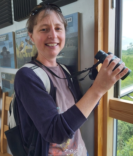 Woman holding binoculars looking at camera