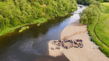 Letters SOS spelt out by people stood on riverside beach