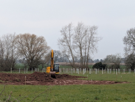 Digger in field next to mound of earth