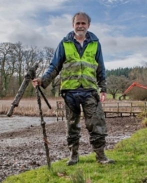 Man in a hi-vis vest and muddy outdoor clothing stood outdoors