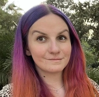Headshot portrait of woman with long purple, pink and orange hair