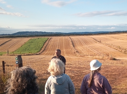 Small group of people stood in front of harvested stubble fields