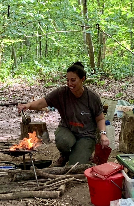 Woman tending to a fire in a fire bowl in a woodland setting