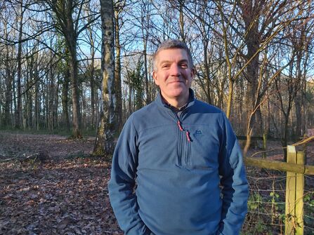 Man standing in woodland in winter with a blue top