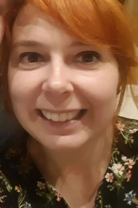 Close up portrait of young woman with auburn hair smiling at camera