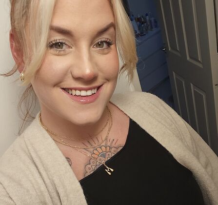 Woman with blonde hair tied back smiling at camera