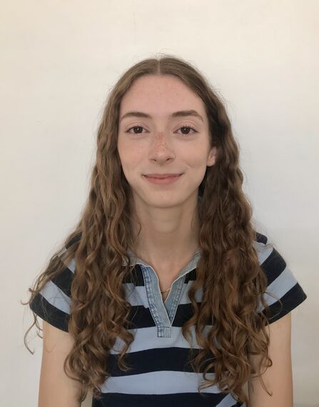 Head and shoulders portrait of woman with long, dark blonde wavy hair wearing a stripey t-shirt