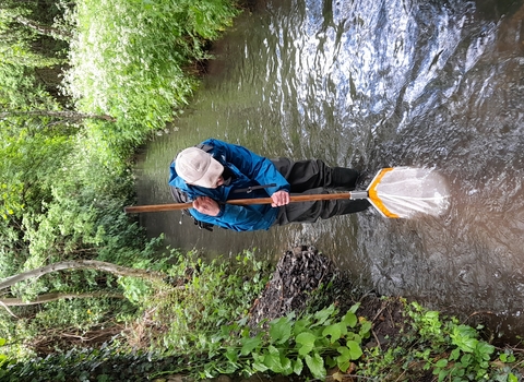 Person stood in stream with net on a pole